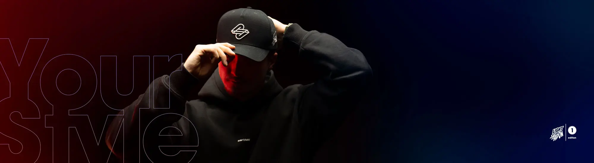 Person in schwarzem RAW2RARE Hoodie und Cap in rot-blauer Beleuchtung