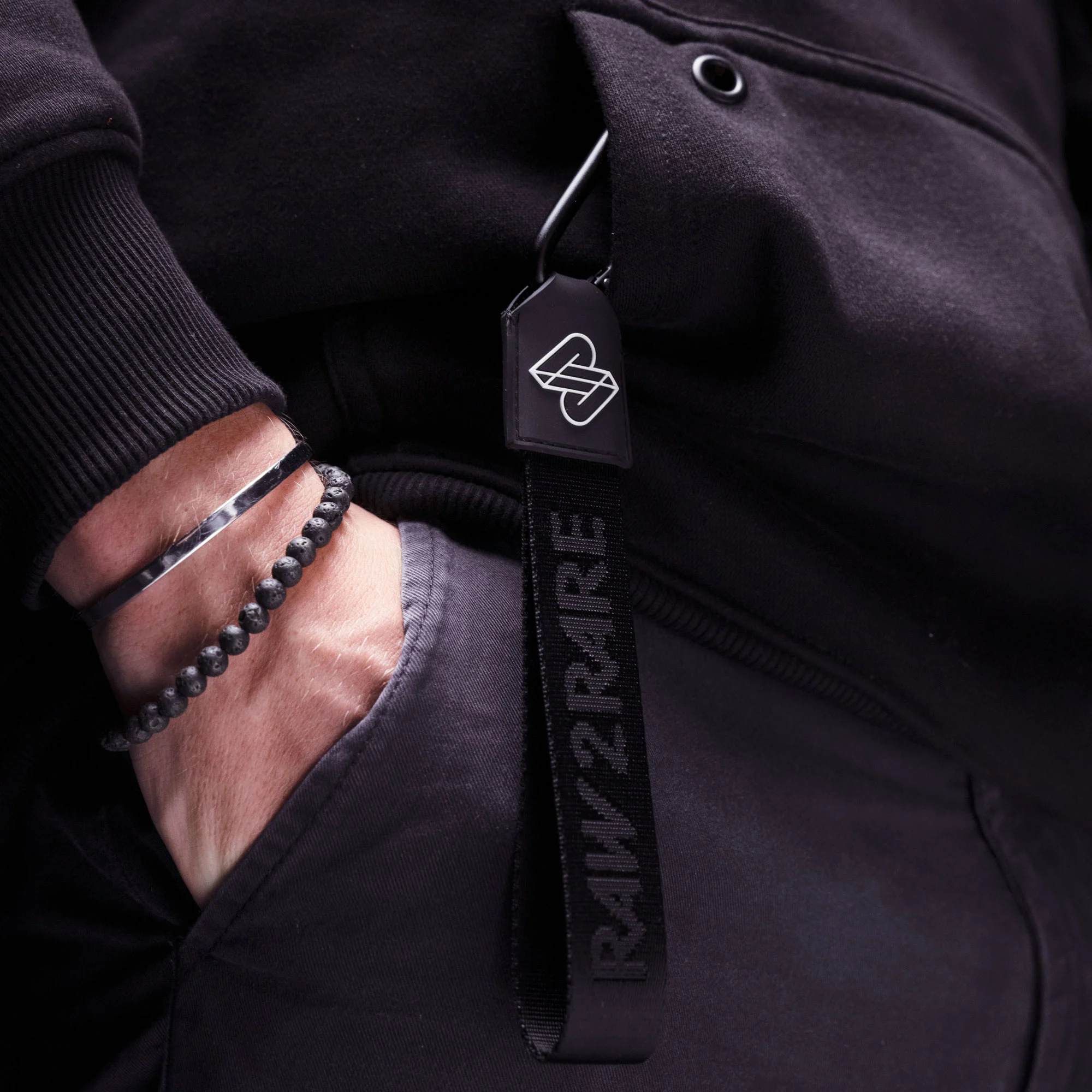 Raw2Rare 2Hook Black – Lifestyle am Hoodie Raw2Rare 2Hook Black – am Hoodie getragen, stylisches Accessoire mit Karabiner und Rubber-Badge
